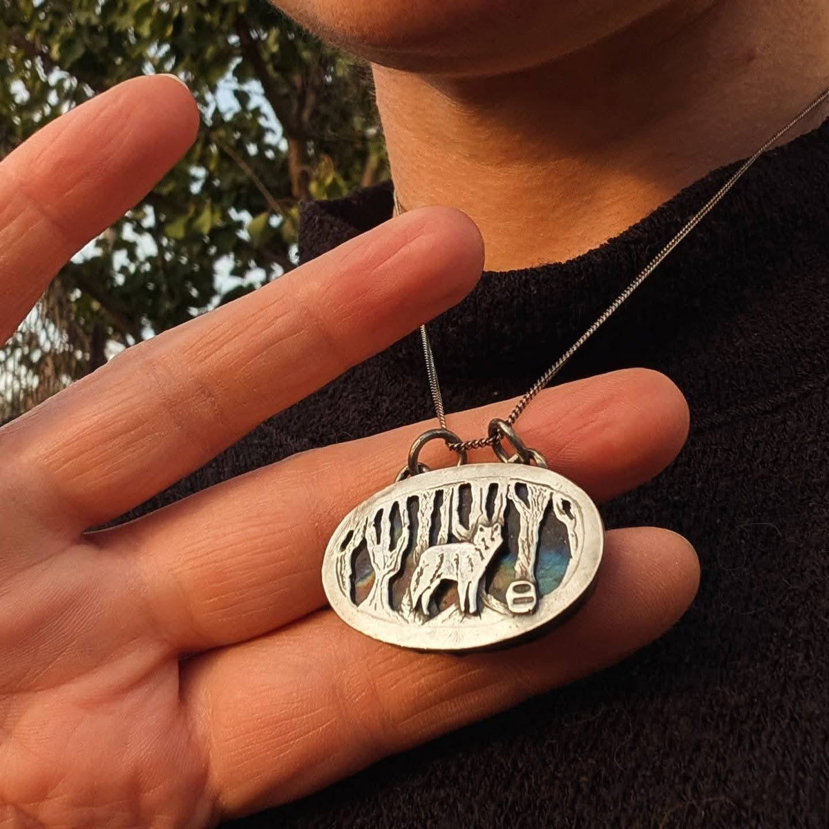 Ciondolo Il Bosco del Lupo indossato, ovale in argento 925 con lupo e alberi su labradorite