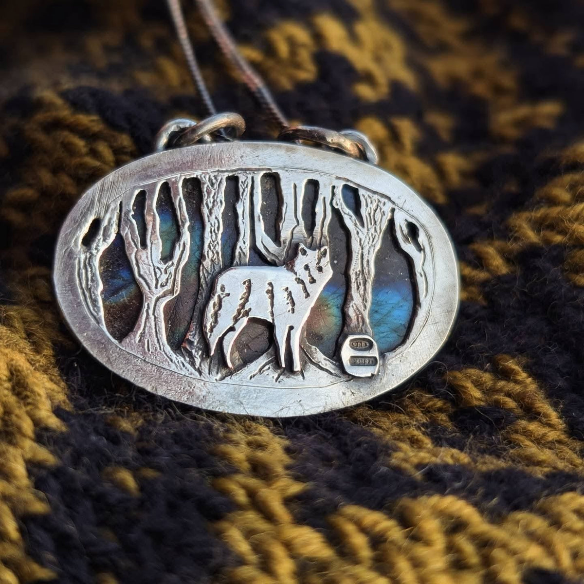 Dettaglio del ciondolo Il Bosco del Lupo: lupo e tronchi in argento 925 con i riflessi blu della labradorite