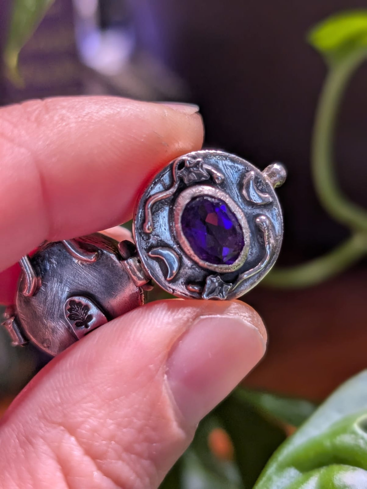 Close-up of the locket: the faceted amethyst and, on the back, the stamped leaf mark
